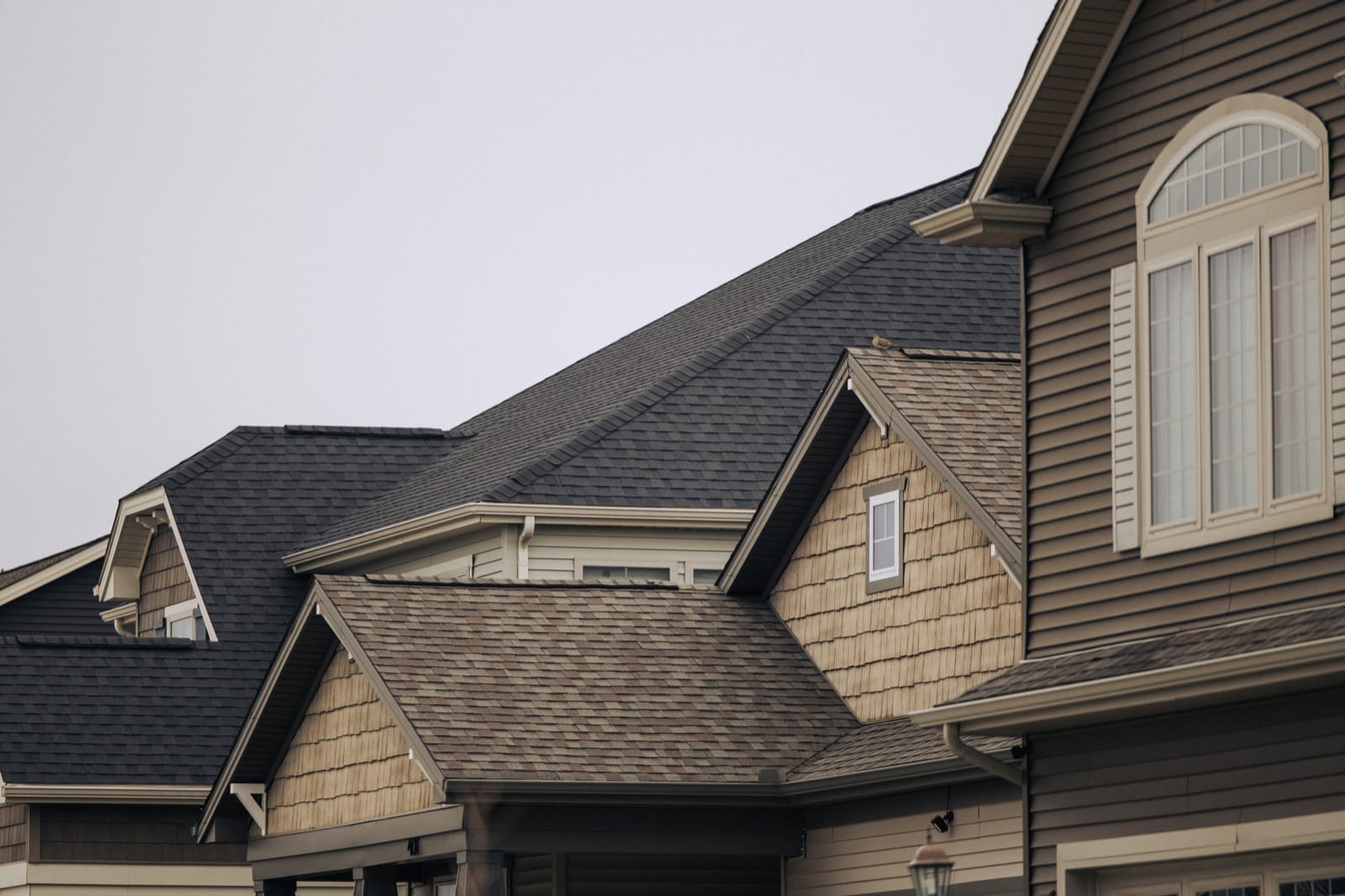 Roofing inspector documenting damage on a residential roof with a tablet